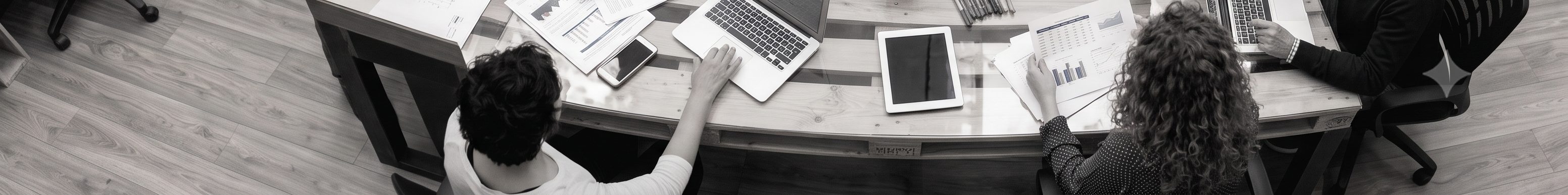 Hands at work across laptops, papers, and notes during a systems design session